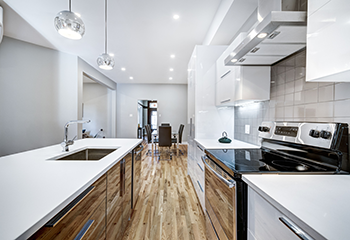 Modern kitchen design featuring white cabinetry, pendant lighting, and stainless steel appliances in San Fernando apartment.